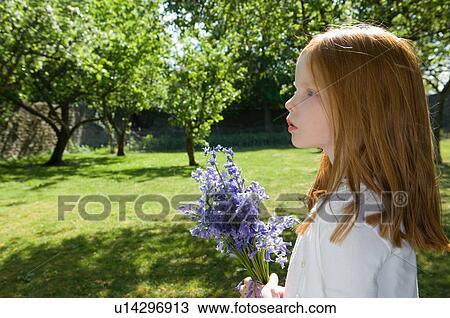 Stock Image - Girl holding flowers in backyard. Fotosearch