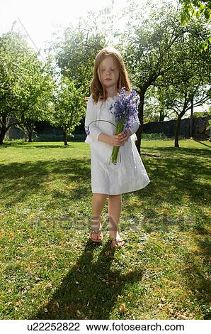 Stock Image - Girl holding flowers in backyard. Fotosearch