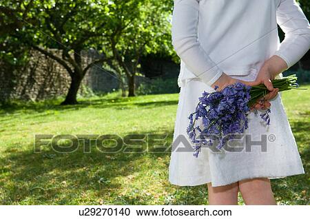 Stock Image - Girl holding flowers in backyard. Fotosearch