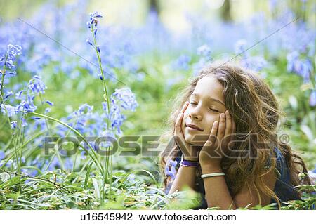 Stock Image - Girl laying in field of flowers. Fotosearch