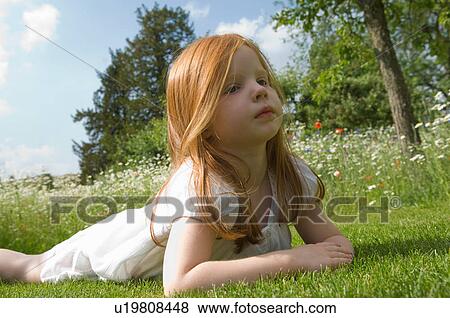 Girl laying on grass in field of flowers View Large Photo Image Stock Photo - Girl laying on grass in field of flowers. Fotosearch