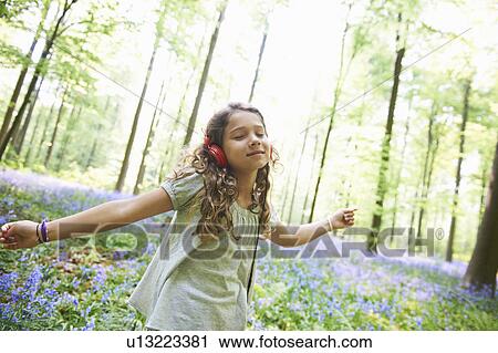 Girl listening to headphones in forest View Large Photo Image Stock Image - Girl listening to headphones in forest. Fotosearch