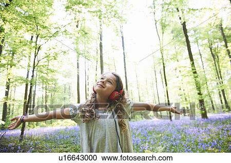 Girl listening to headphones in forest View Large Photo Image Stock Image - Girl listening to headphones in forest. Fotosearch