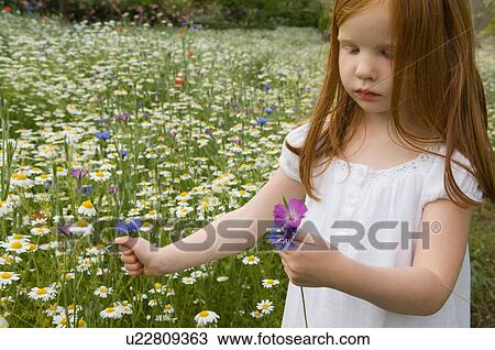 Stock Image - Girl picking flowers in field. Fotosearch