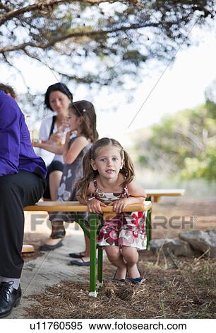 Girl playing on bench with family View Large Photo Image Stock Photography - Girl playing on bench with family. Fotosearch
