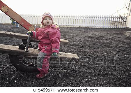 Stock Image - Girl playing on seesaw at playground. Fotosearch