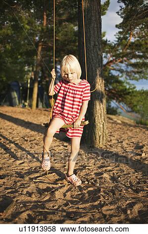Stock Photo - Girl playing on tree swing in forest. Fotosearch