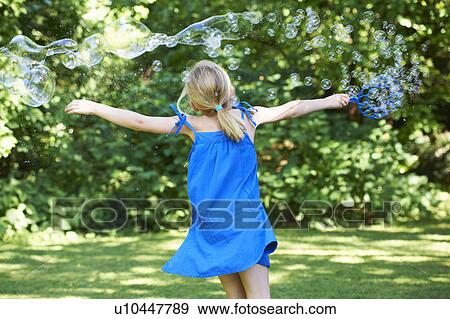 Girl playing with bubbles in backyard View Large Photo Image Stock Photo - Girl playing with bubbles in backyard. Fotosearch