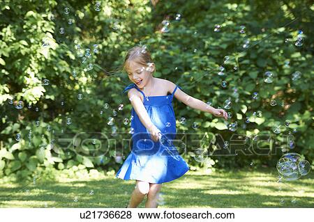 Stock Photo - Girl playing with bubbles in backyard. Fotosearch