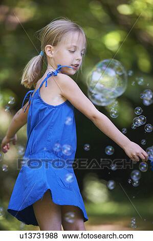 Stock Photo - Girl playing with bubbles outdoors. Fotosearch