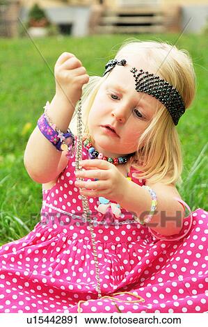 Stock Image - Girl playing with jewelry in backyard. Fotosearch