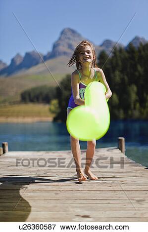 Girl playing with pool toy on jetty View Large Photo Image Stock Photo - Girl playing with pool toy on jetty. Fotosearch