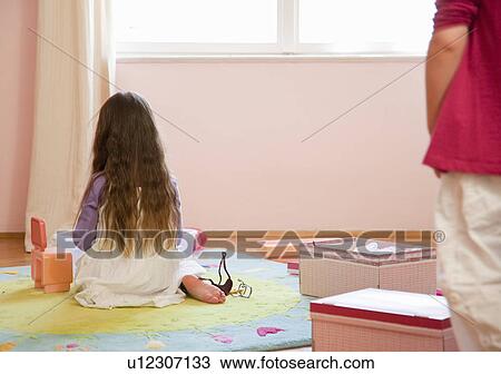 Stock Image - Girl playing with toys on rug. Fotosearch