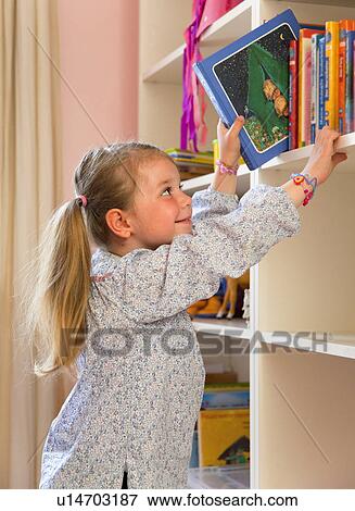 Girl pulling books from bookshelf View Large Photo Image Stock Photo - Girl pulling books from bookshelf. Fotosearch