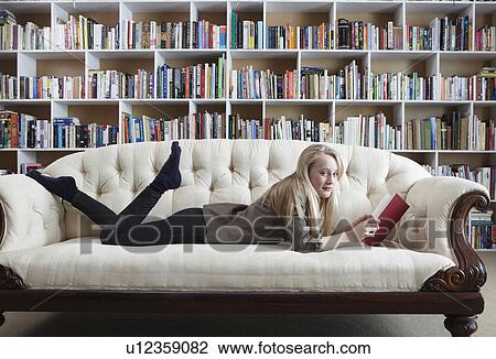 Stock Image - Girl reading on couch in library. Fotosearch