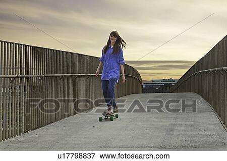 Girl riding skateboard on walkway View Large Photo Image Stock Photo - Girl riding skateboard on walkway. Fotosearch