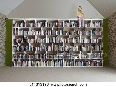 Stock Photograph - Girl sitting on top of bookshelves. Fotosearch