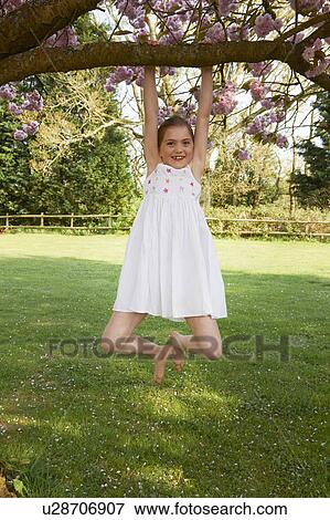 Girl swinging from tree in backyard View Large Photo Image Stock Photo - Girl swinging from tree in backyard. Fotosearch