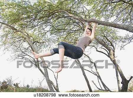 Stock Photo - Girl swinging from tree outdoors. Fotosearch