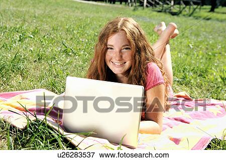 Girl using laptop on grass View Large Photo Image Stock Photo - Girl using laptop on grass. Fotosearch
