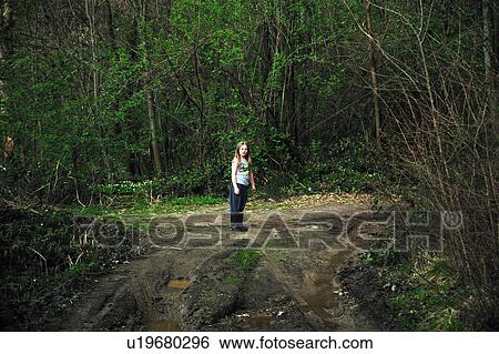 Stock Photograph - Girl walking on dirt road in forest. Fotosearch