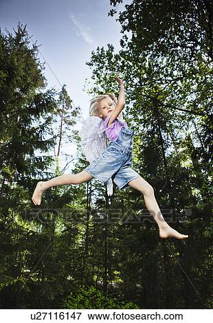 Stock Photo - Girl wearing wings and jumping in forest. Fotosearch