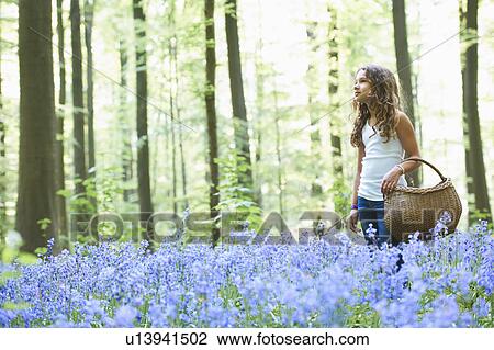 Stock Image - Girl with basket in field of flowers. Fotosearch