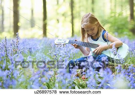 Stock Photo - Girl with guitar in field of flowers. Fotosearch