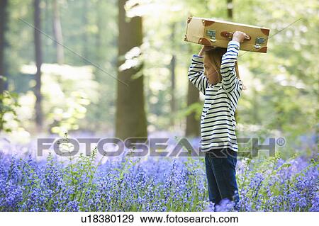 Stock Photo - Girl with luggage in field of flowers. Fotosearch