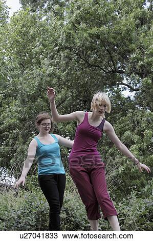Stock Image - Girls balancing on walkway in park. Fotosearch