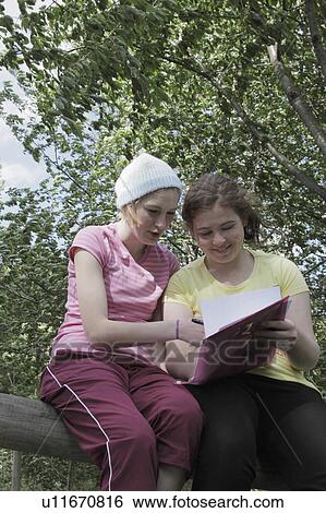 Girls doing homework together in park View Large Photo Image Stock Photograph - Girls doing homework together in park. Fotosearch