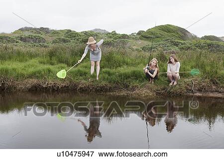 Stock Photo - Girls fishing with nets in creek. Fotosearch