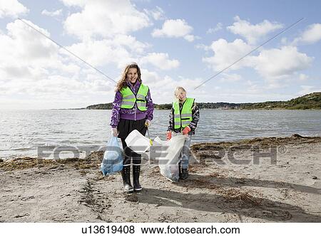 Stock Photo - Girls in safety vests cleaning beach. Fotosearch