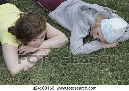 Stock Photograph - Girls laying in grass at park. Fotosearch
