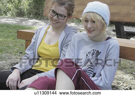 Picture - Girls leaning on park bench. Fotosearch