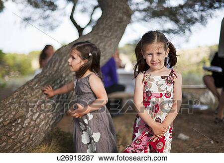 Stock Photo - Girls playing by tree outdoors. Fotosearch