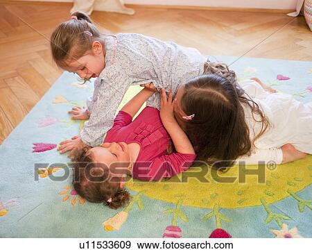 Stock Photo - Girls playing together on rug. Fotosearch