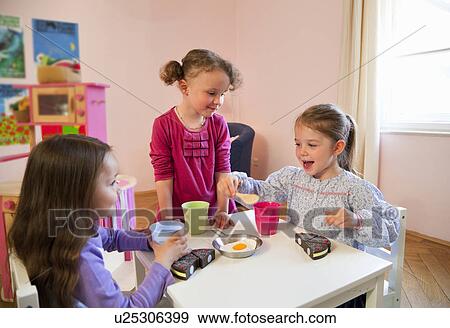 Stock Photo - Girls playing with toy kitchen. Fotosearch