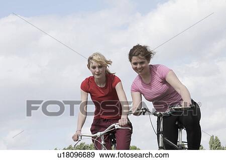 Stock Photo - Girls riding bikes outdoors. Fotosearch