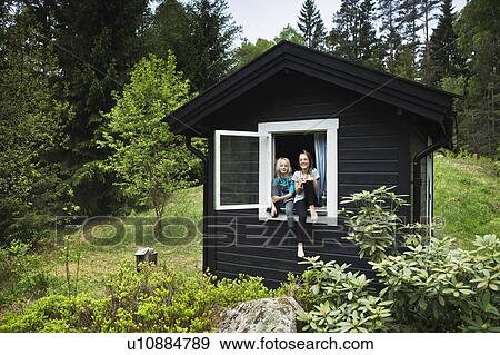 Stock Photo - Girls sitting in window of shack. Fotosearch