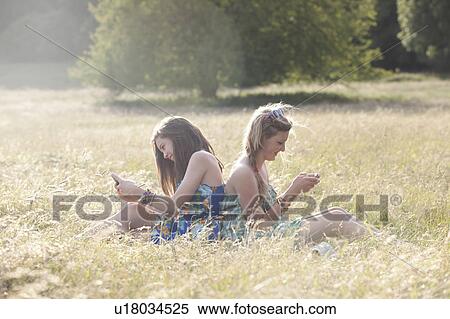 Girls using cell phones in field View Large Photo Image Stock Photography - Girls using cell phones in field. Fotosearch