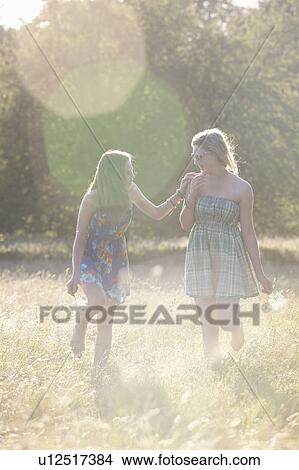 Picture - Girls walking together in field. Fotosearch
