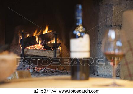 Glass of wine and bottle by fireplace View Large Photo Image Picture - Glass of wine and bottle by fireplace. Fotosearch