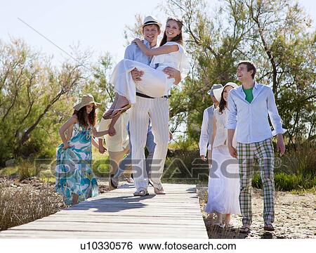Groom carrying bride on deck View Large Photo Image Stock Photograph - Groom carrying bride on deck. Fotosearch