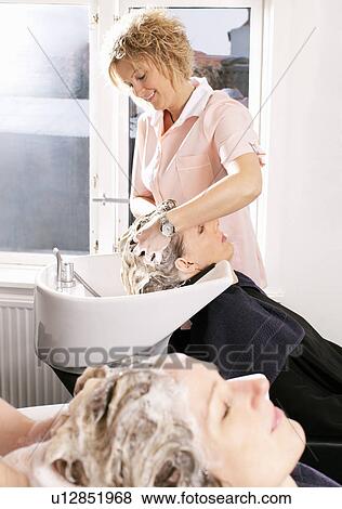 Stock Photo - Hairdresser washing woman’s hair. Fotosearch