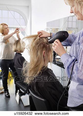 Stock Image - Hairdressers at work in salon. Fotosearch