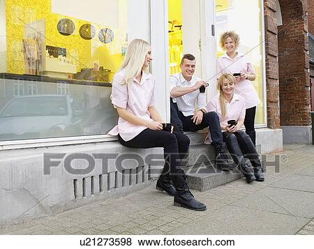 Stock Photo - Hairdressers having coffee outside salon. Fotosearch