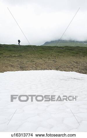 Hiker on mountainside with melting snow View Large Photo Image Picture - Hiker on mountainside with melting snow. Fotosearch