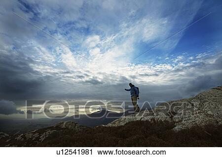 Stock Image - Hiking man admiring mountain view. Fotosearch