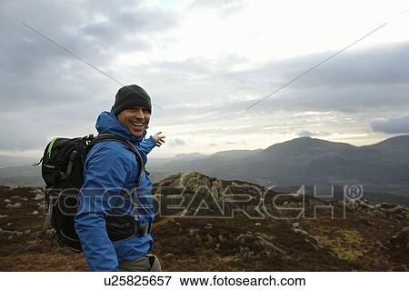 Stock Photo - Hiking man admiring mountain view. Fotosearch